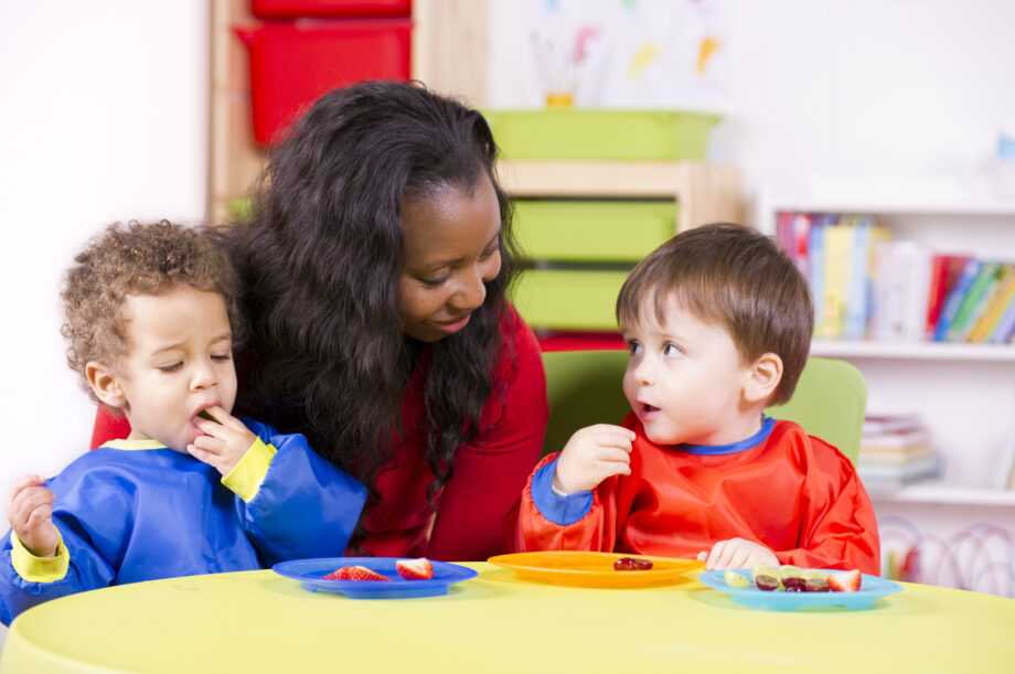 A woman and two children eating at a table in a classroom.